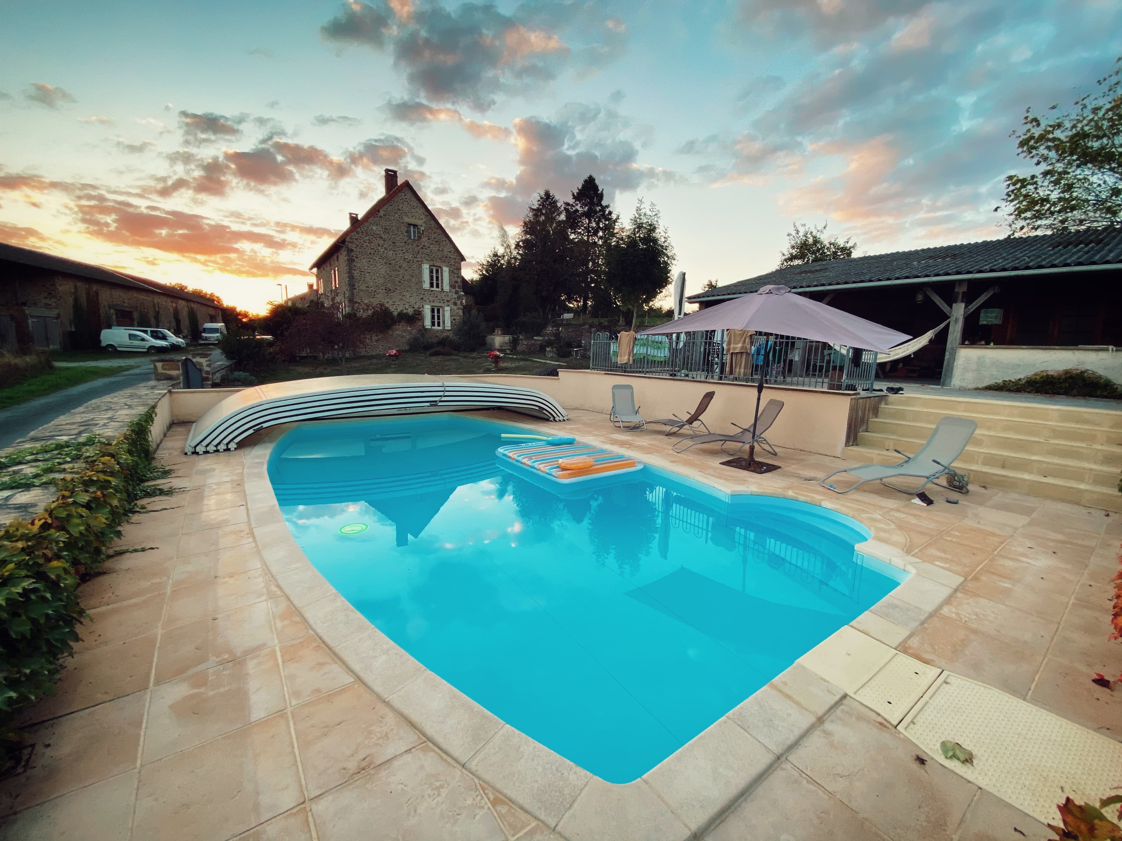 Pool at sunset with stone terrace and farmhouse